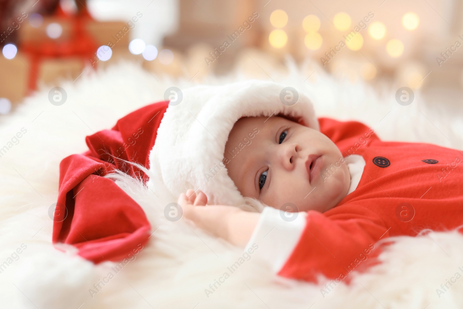 Photo of Cute baby in Christmas costume lying on fur rug