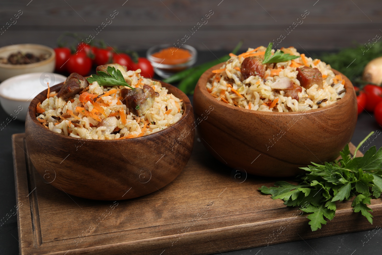 Photo of Delicious pilaf with meat and carrot in bowls on black table, closeup