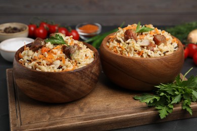Photo of Delicious pilaf with meat and carrot in bowls on black table, closeup