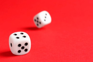 Many white game dices falling on red background. Space for text