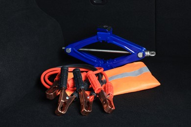 Scissor jack, life vest and battery jumper cables in trunk. Car safety equipment