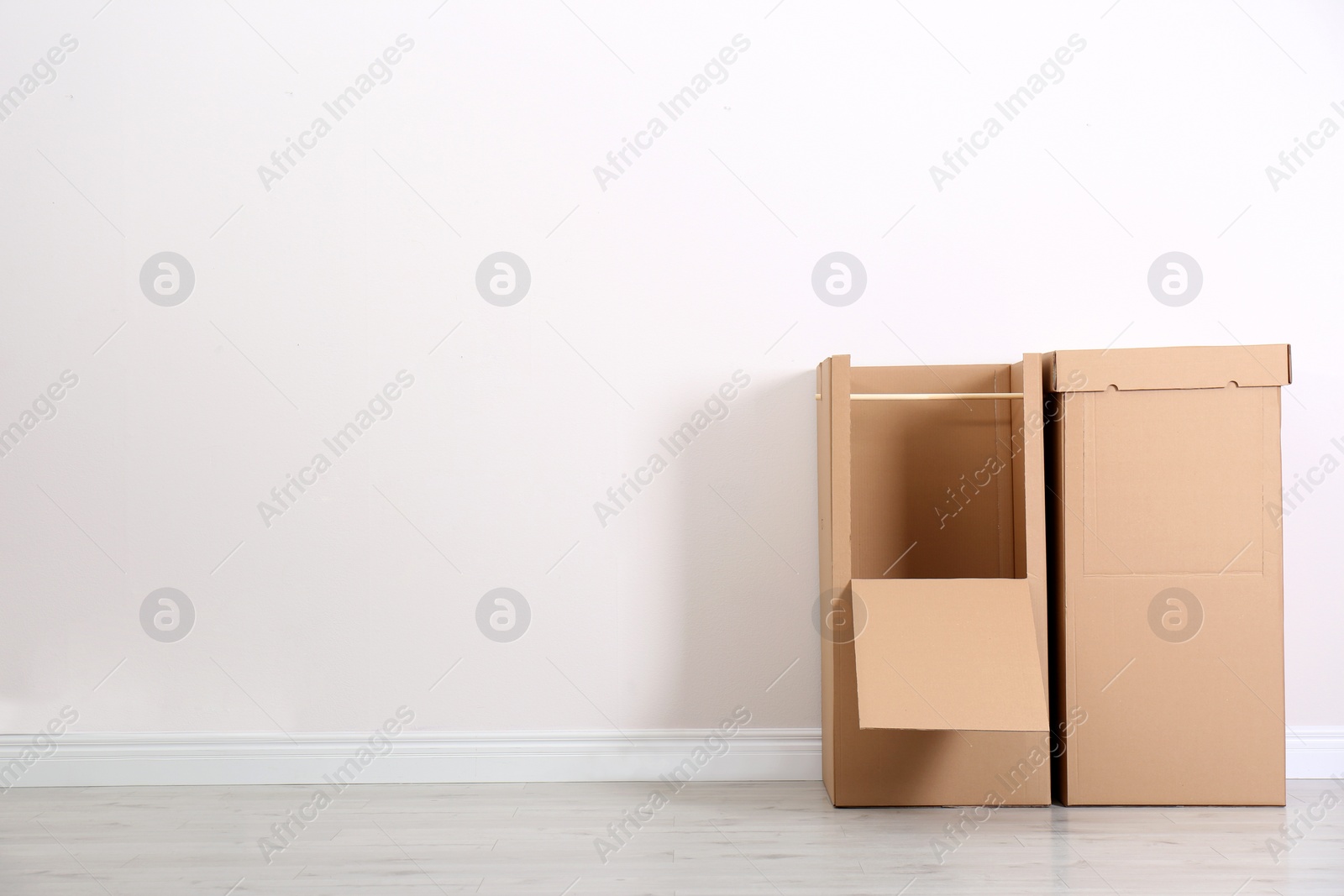 Photo of Cardboard wardrobe boxes against light wall indoors. Space for text