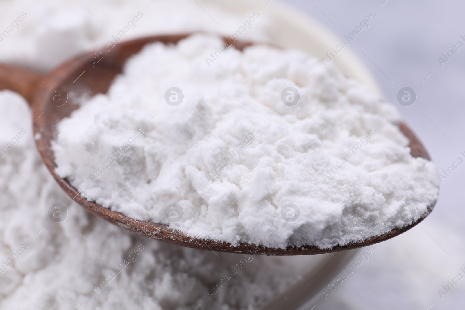 Photo of Heap of natural starch and wooden spoon, closeup