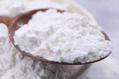 Photo of Heap of natural starch and wooden spoon, closeup