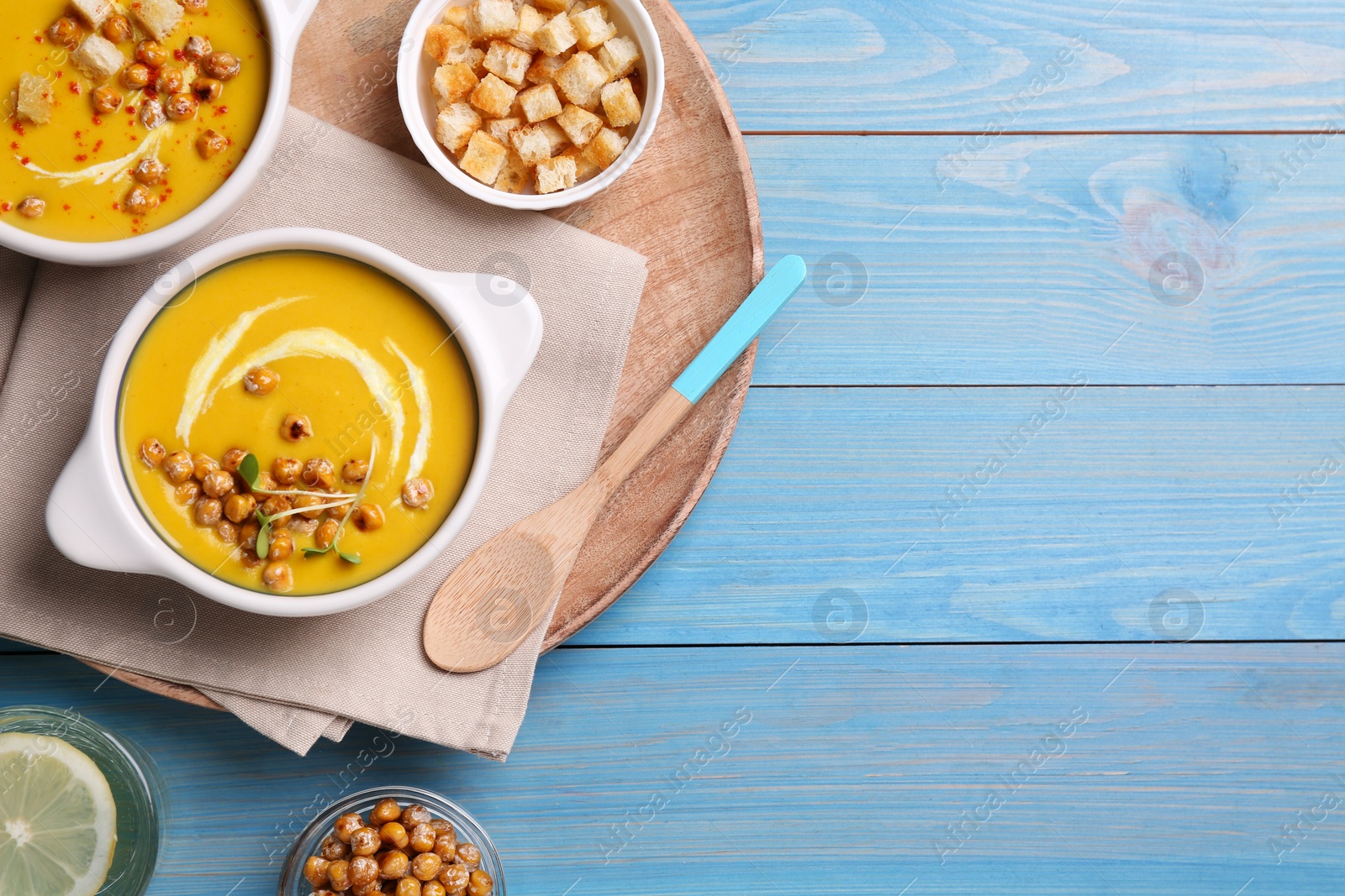 Photo of Delicious cream soup with chickpeas on light blue wooden table, flat lay. Space for text