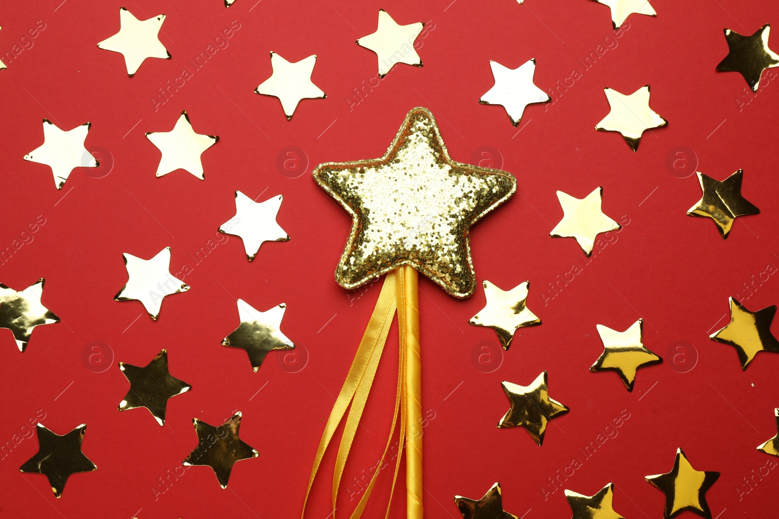 Photo of Beautiful golden magic wand and confetti on red background, flat lay