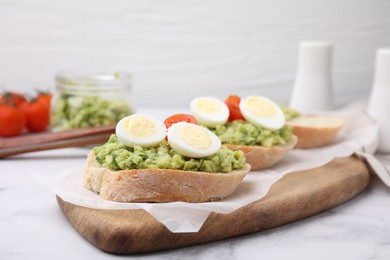 Photo of Delicious sandwiches with guacamole, eggs and tomatoes on table