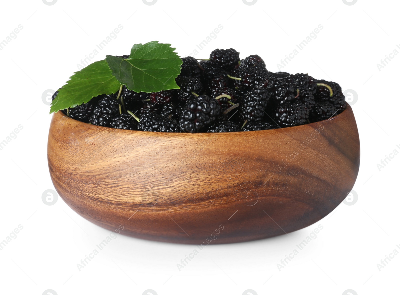 Photo of Ripe black mulberries and leaves in wooden bowl on white background