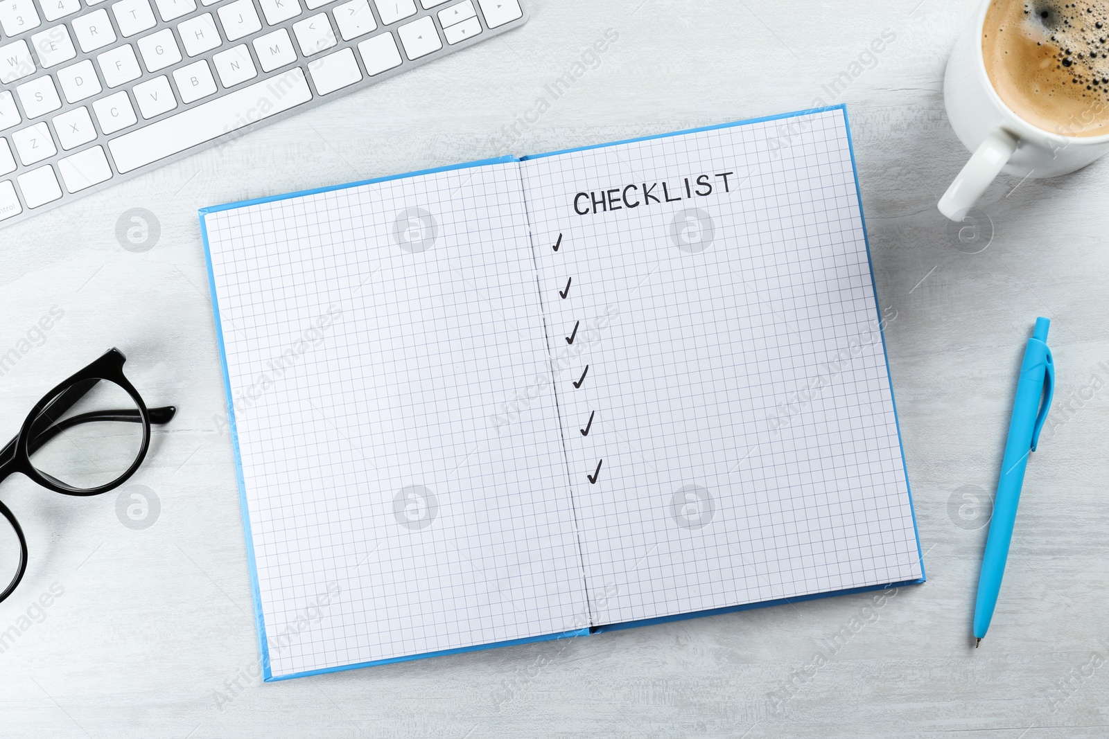 Photo of Notebook with inscription Checklist, computer keyboard, cup of coffee and eyeglasses on white wooden table, flat lay