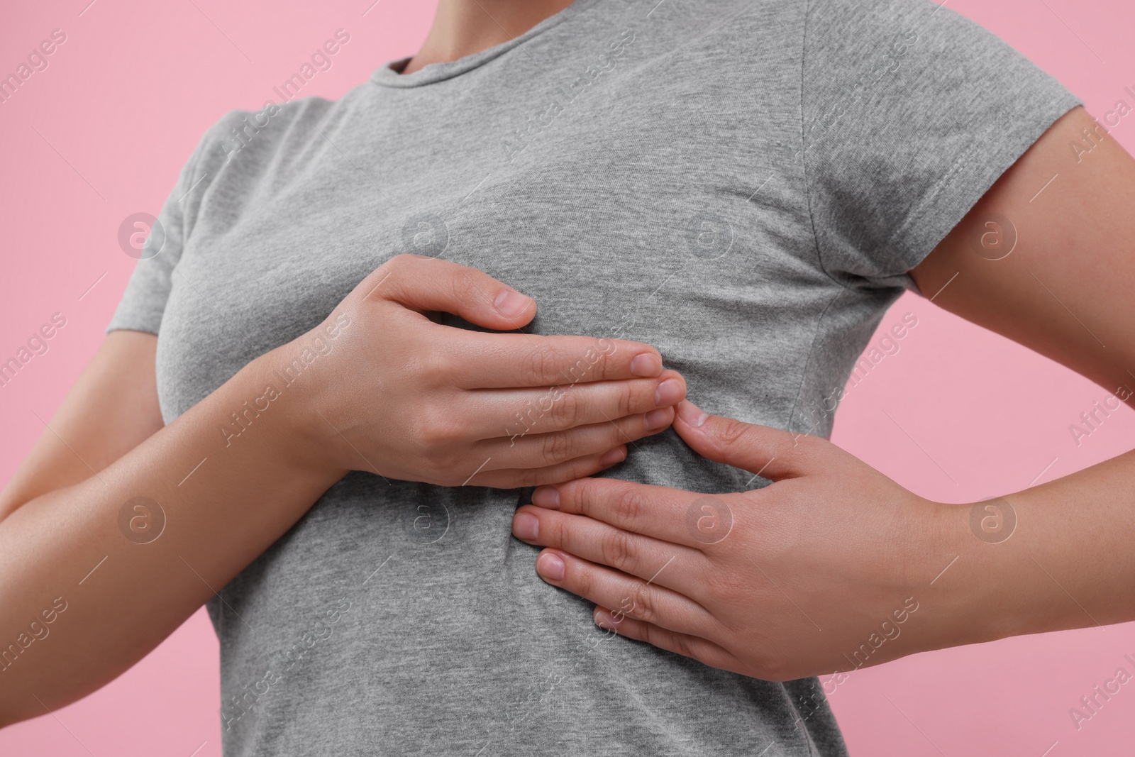 Photo of Woman doing breast self-examination on pink background, closeup