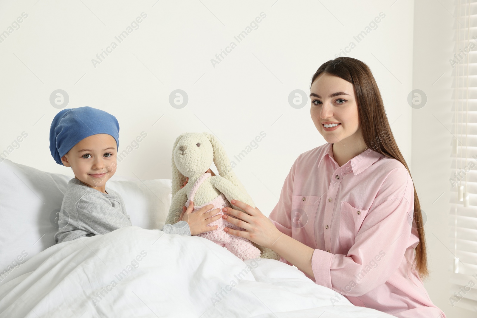 Photo of Childhood cancer. Mother and daughter with toy bunny in hospital