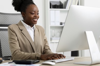 Photo of Professional accountant working on computer at wooden desk in office