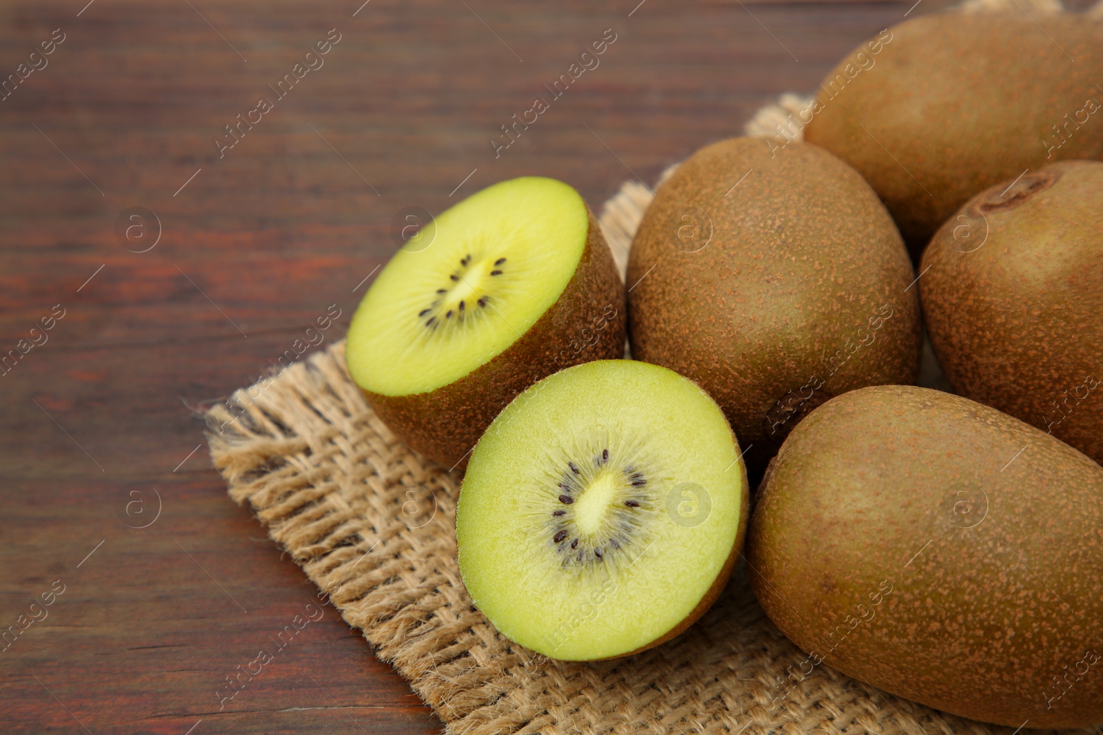 Photo of Whole and cut fresh kiwis on wooden table, closeup