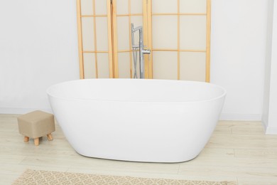 Photo of Beautiful white tub and ottoman in bathroom. Interior design