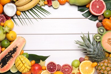 Frame of different exotic fruits on white wooden background, flat lay. Space for text