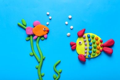 Seaweed and fish made of plasticine on light blue background, flat lay