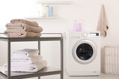 Stacked clean soft towels on table in laundry room. Space for text