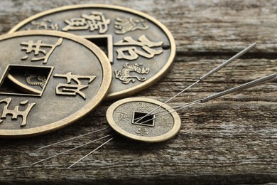 Photo of Acupuncture needles and Chinese coins on wooden table, closeup