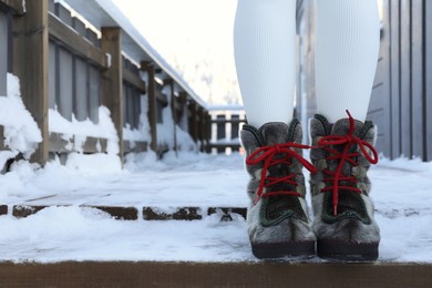 Photo of Woman in comfortable boots on snowy day outdoors, closeup with space for text. Winter vacation