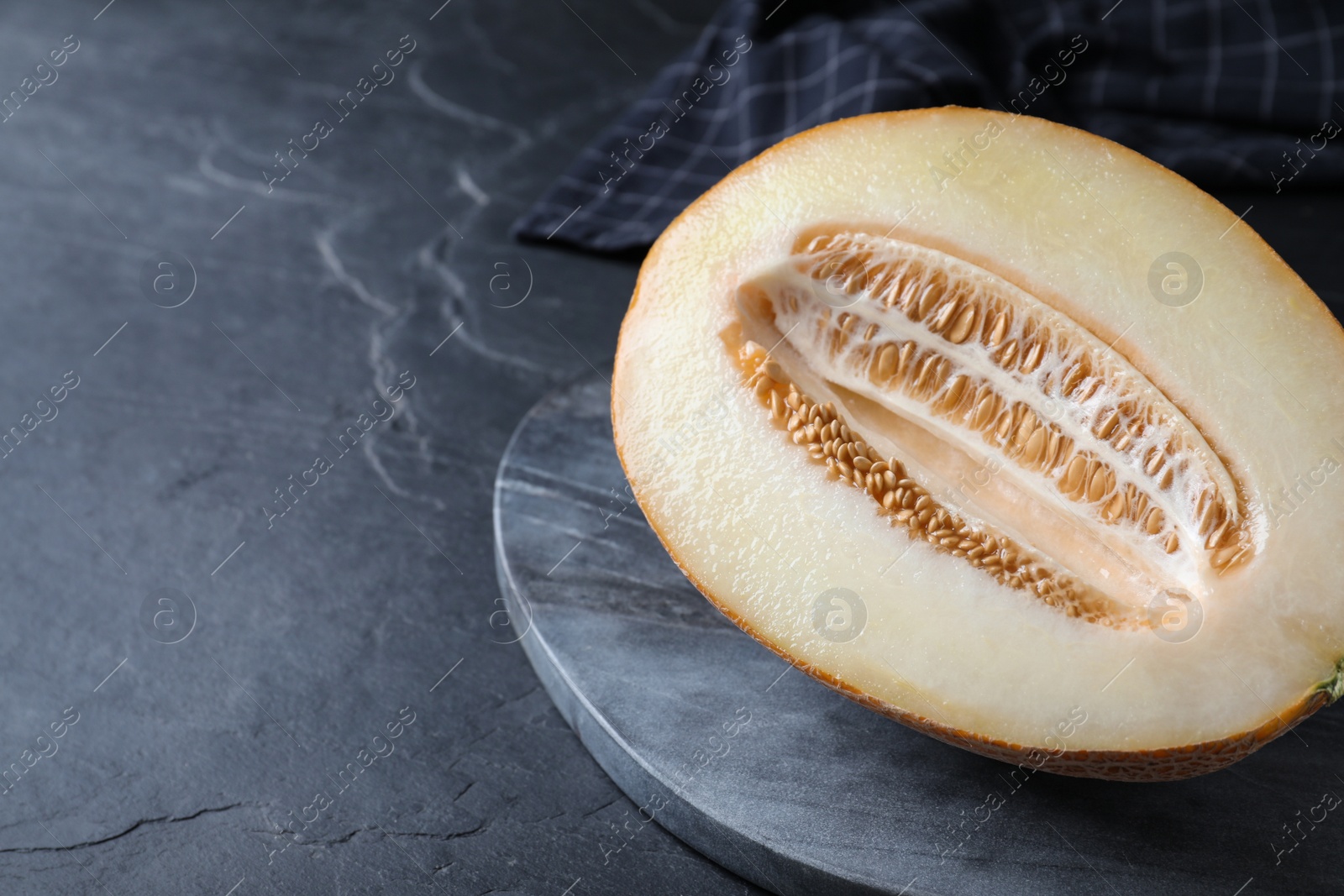 Photo of Delicious honey melon on black table, closeup. Space for text