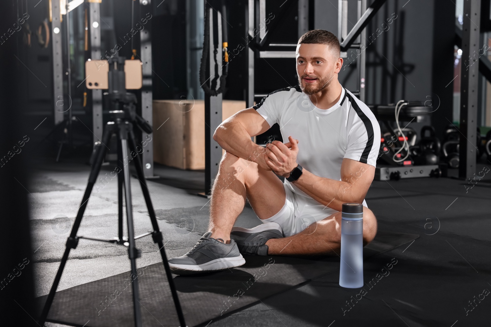 Photo of Trainer streaming online workout with phone at gym