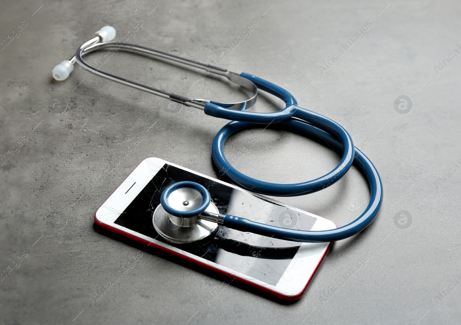 Photo of Modern smartphone with broken display and stethoscope on table. Device repair service