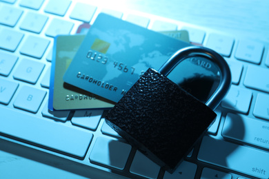 Photo of Credit cards, lock and computer keyboard on table, closeup. Cyber crime