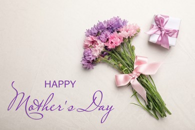 Happy Mother's Day. Greeting card with gift box and bouquet of beautiful flowers on light beige background, flat lay