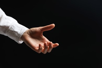 Photo of Woman holding something in hand on black background, closeup. Space for text