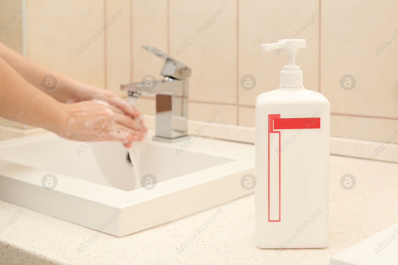 Photo of Woman washing hands in public bathroom, focus on antiseptic gel dispenser