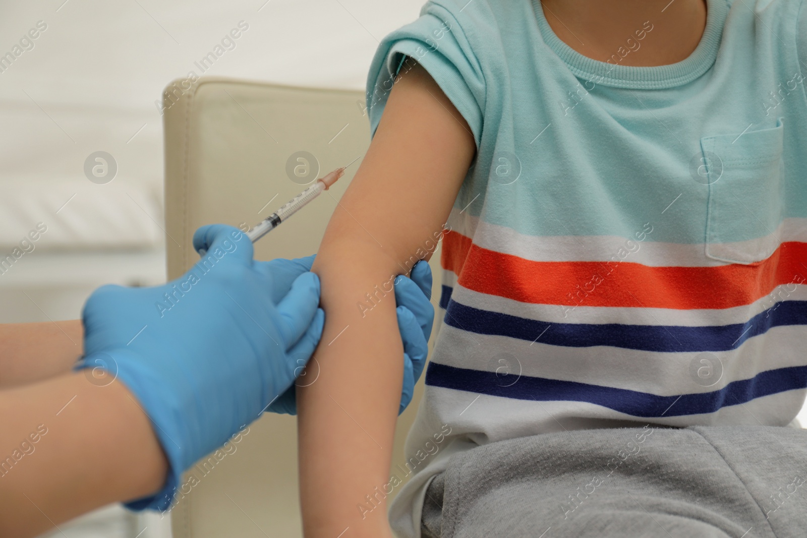 Photo of Nurse vaccinating little boy in clinic, closeup. Immunization concept