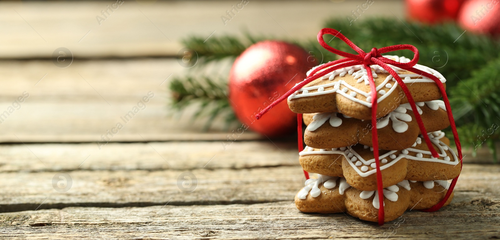 Photo of Tasty Christmas cookies with icing on wooden table, closeup. Space for text