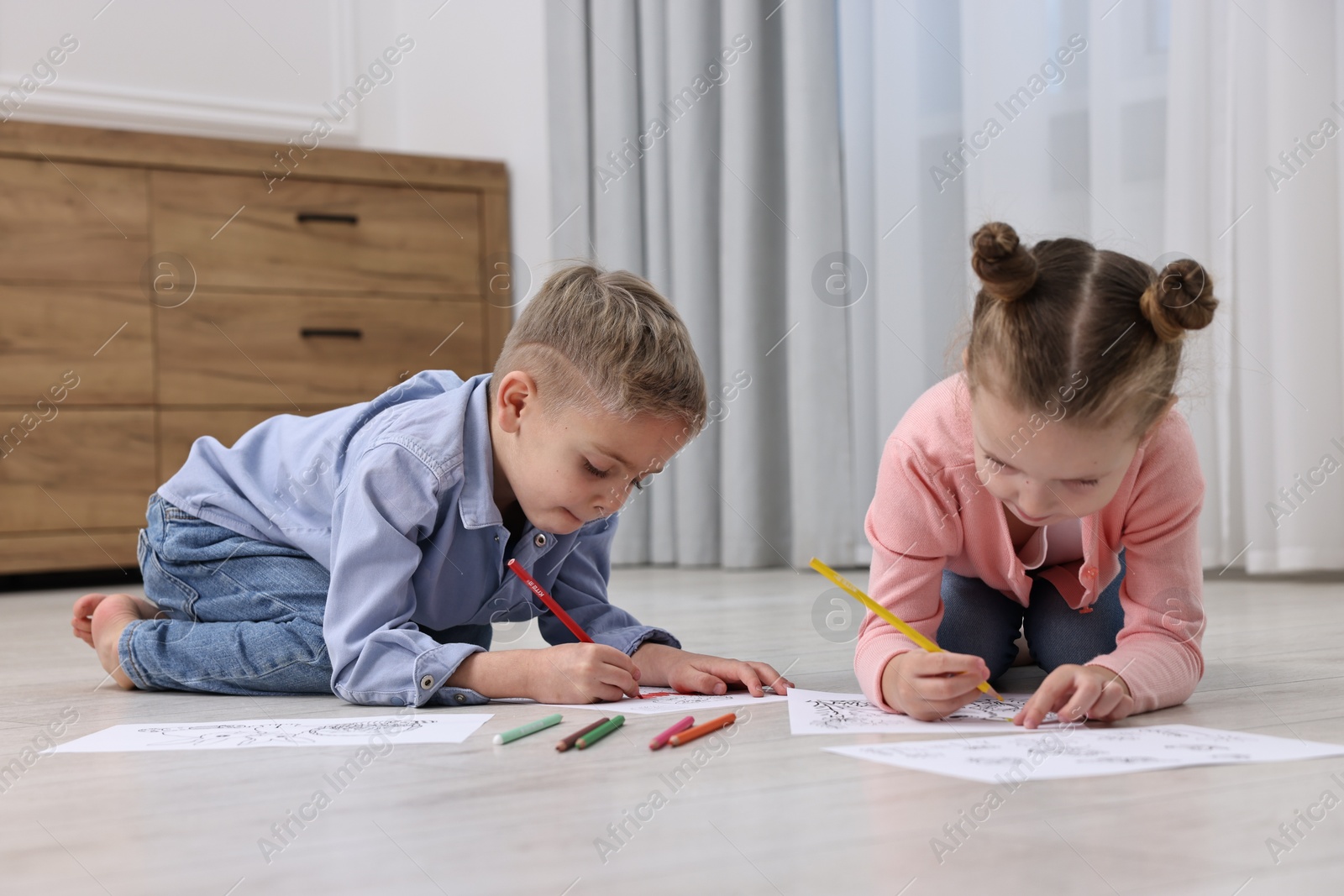 Photo of Cute little children coloring on warm floor at home. Heating system