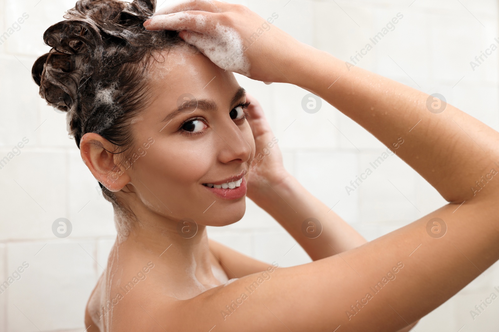 Photo of Happy woman washing hair while taking shower at home