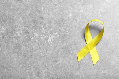 Photo of Yellow ribbon on grey background, top view. Cancer awareness