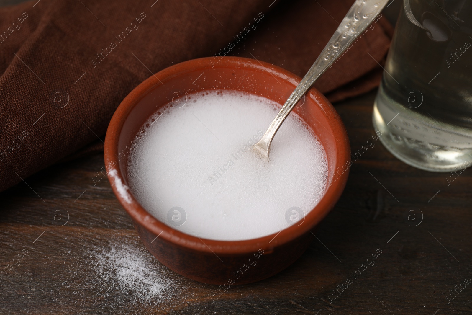 Photo of Chemical reaction of vinegar and baking soda in bowl on wooden table, closeup