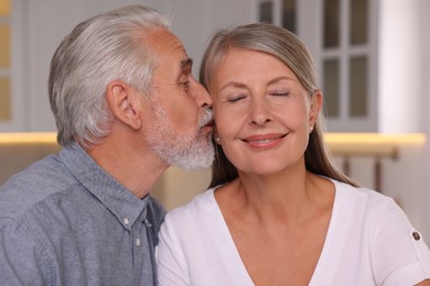 Senior man kissing his beloved woman indoors