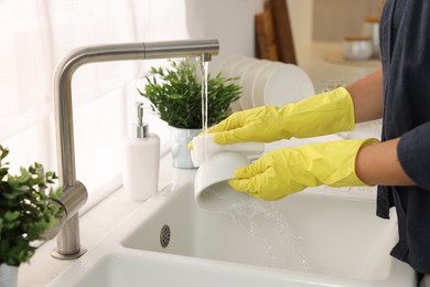 Photo of Woman washing cup at sink in kitchen, closeup