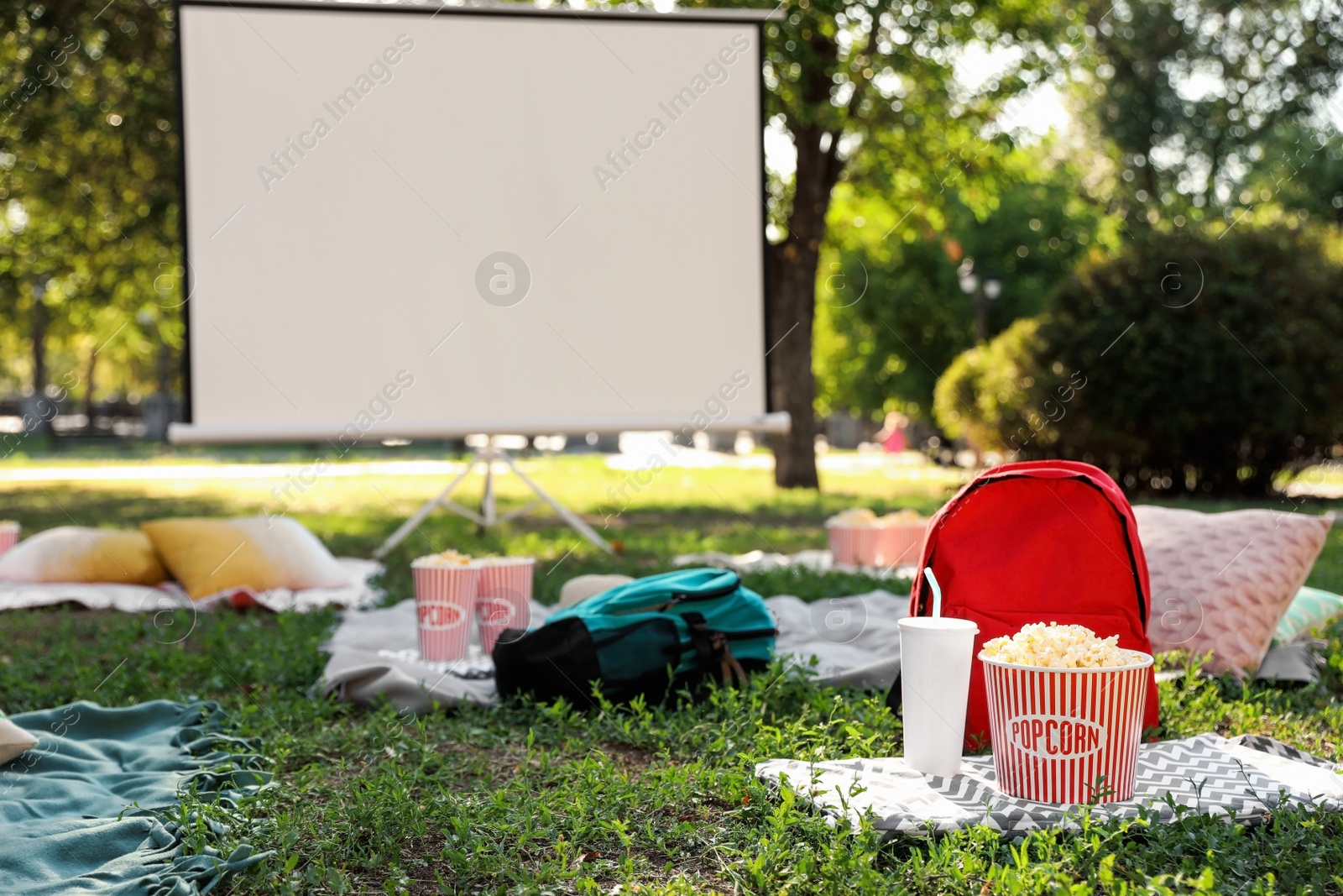 Photo of Popcorn and drink on green grass in open air cinema. Space for text