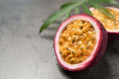 Photo of Half of passion fruit (maracuya) on grey table, closeup. Space for text