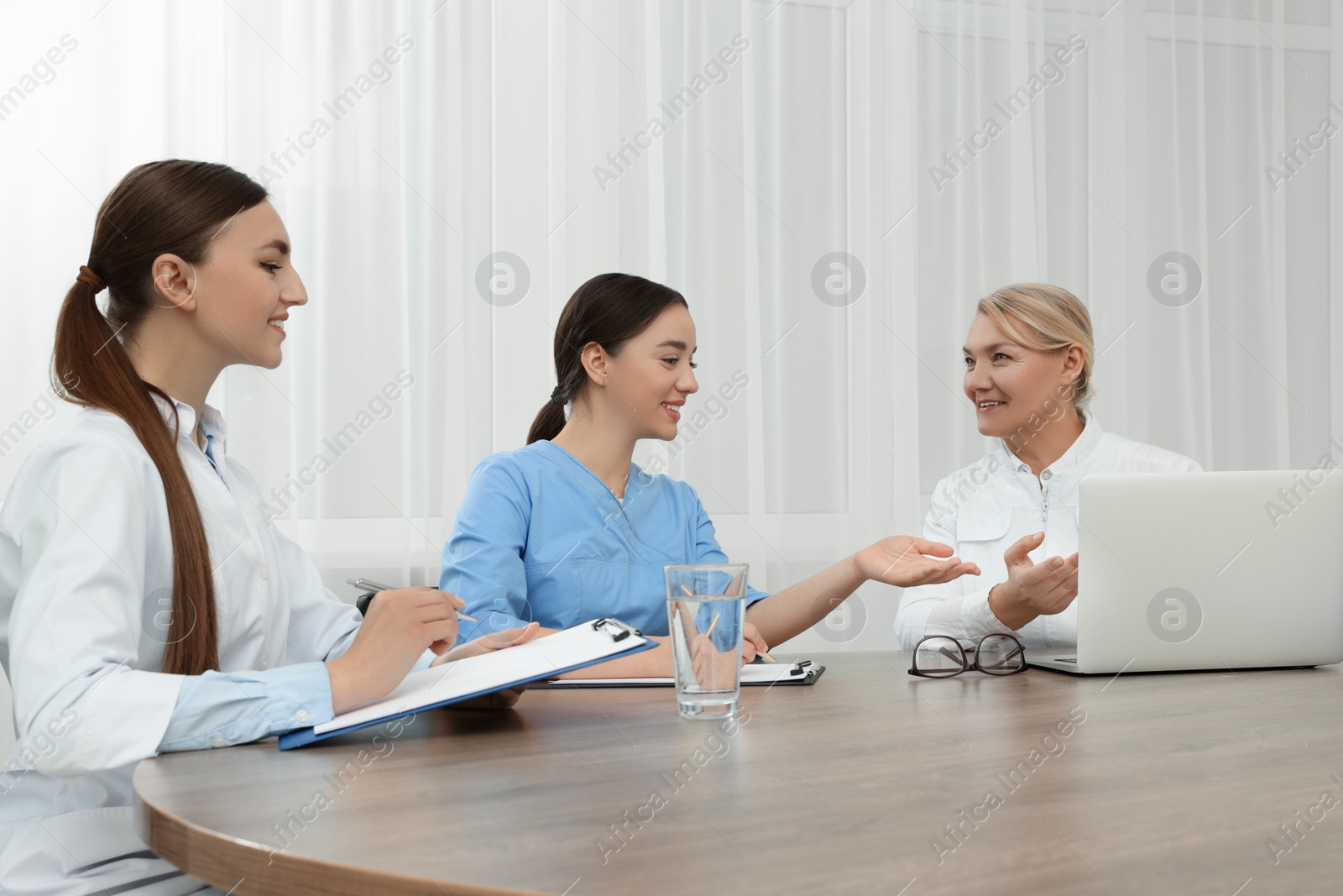 Photo of Medical conference. Doctors having discussion at wooden table in office