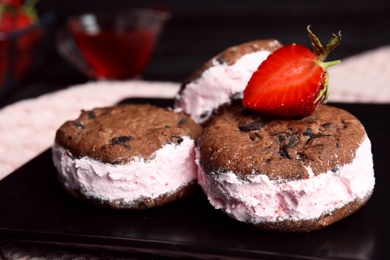 Photo of Sweet delicious ice cream cookie sandwiches with strawberry on plate, closeup