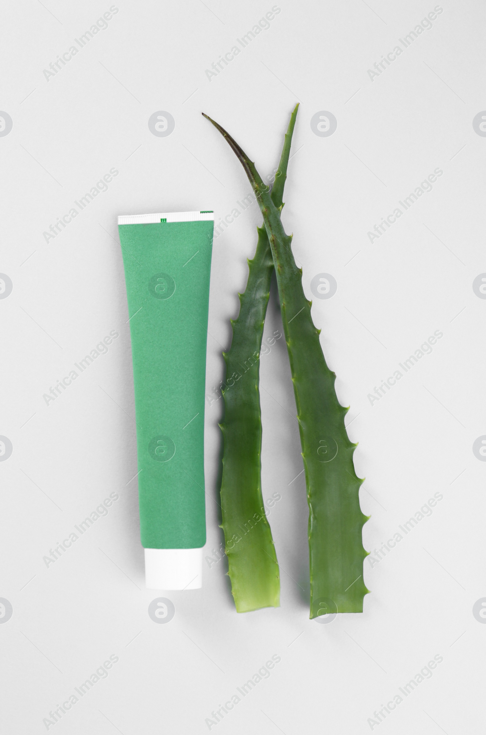 Photo of Tube of toothpaste and fresh aloe on white background, top view