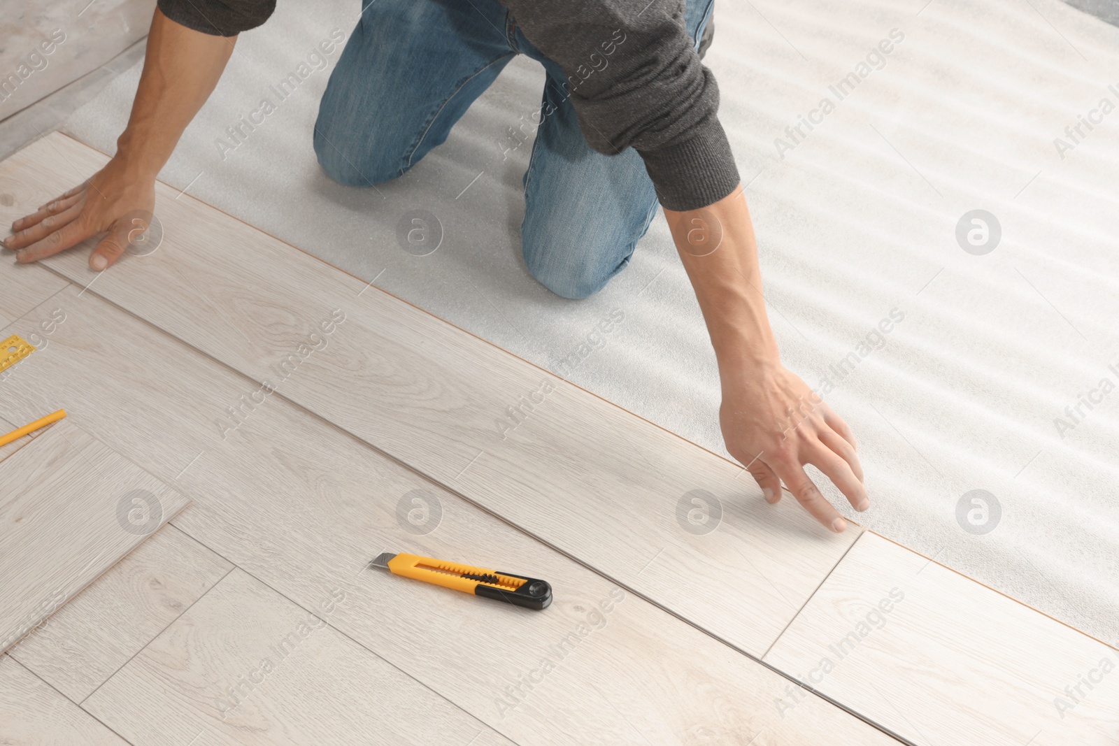 Photo of Worker installing new laminate flooring in room, closeup