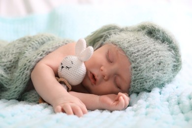 Photo of Cute newborn baby with toy sleeping on soft blanket, closeup