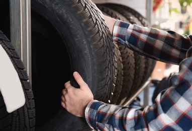 Photo of Male mechanic with car tires in automobile service center, closeup