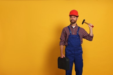 Photo of Professional builder in uniform with hammer and toolbox on yellow background, space for text