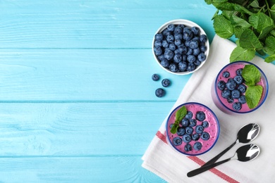 Flat lay composition of fresh blueberry smoothie and space for text on light blue wooden table