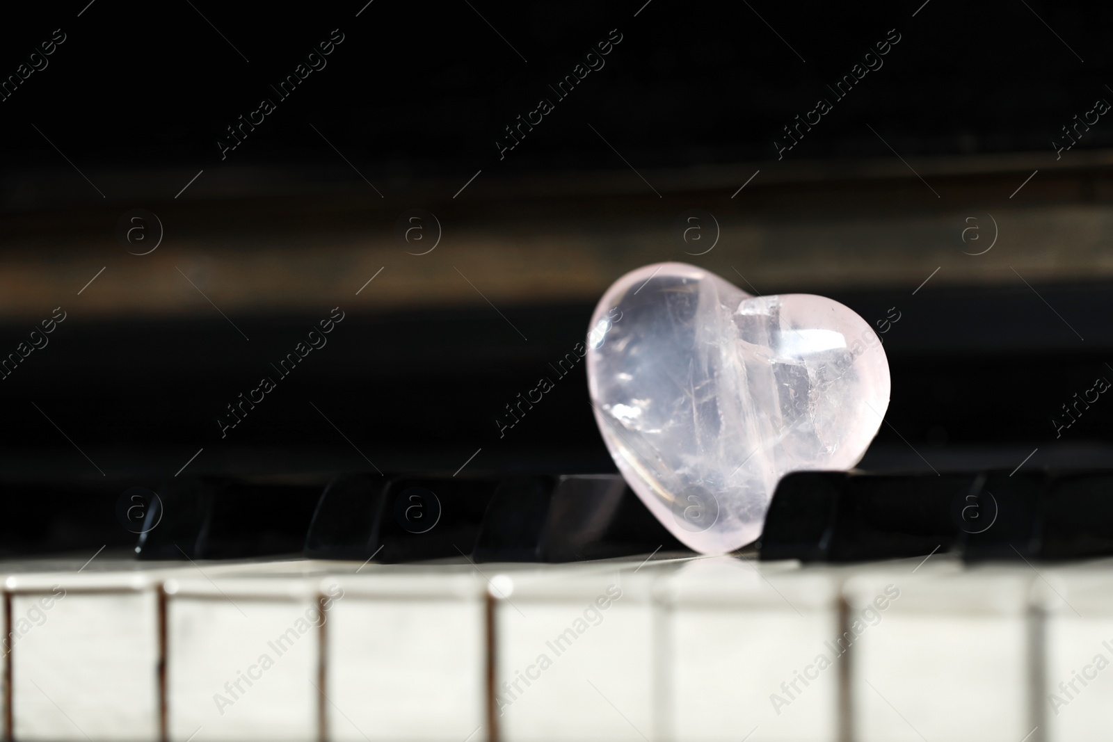 Photo of Beautiful heart shaped stone on piano keys, closeup. Space for text