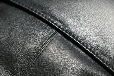 Black natural leather with seams as background, closeup view